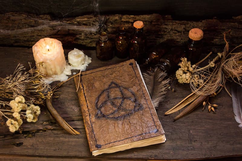 Un grimoire de correspondances magiques avec un symbole triquetra et des outils ésotériques