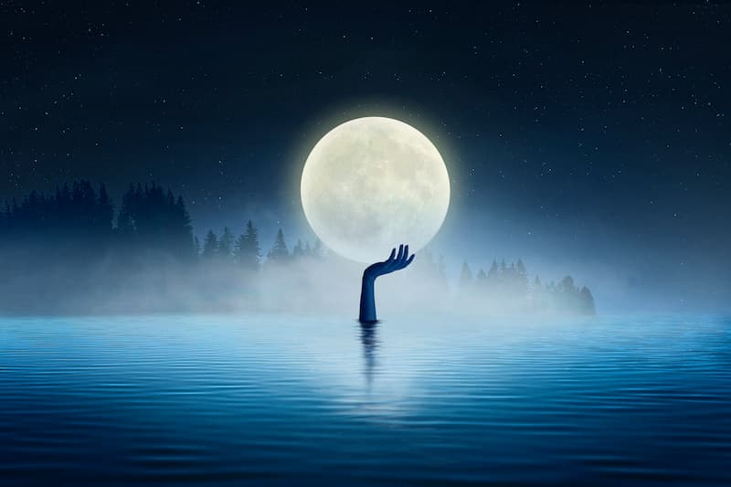 Une main de femme sortant de l'eau d'un lac en portant la pleine lune