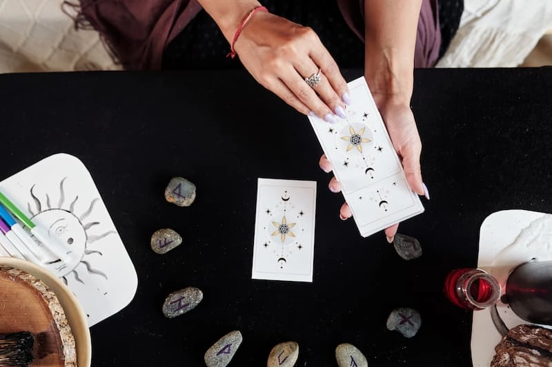 Une femme tire une carte dans un jeu d'oracle divinatoire sur une table avec des runes