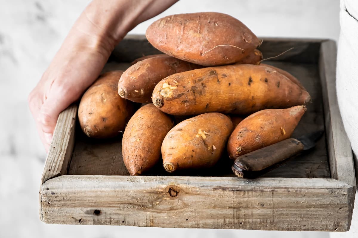 Patates douces dans une caisse en bois prêtes pour de la cuisine magique
